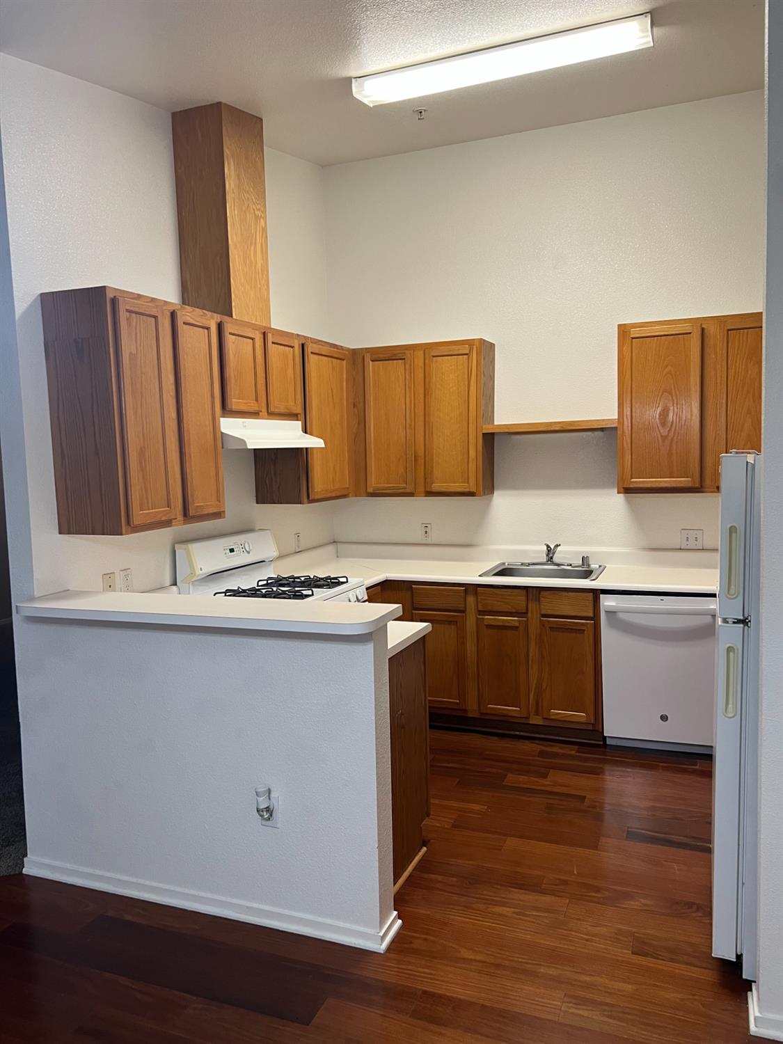 565 Peerless Way, Unit 302 Tracy, CA 95376 - Photo 12 of 17 a kitchen with granite countertop a sink cabinets and wooden floor