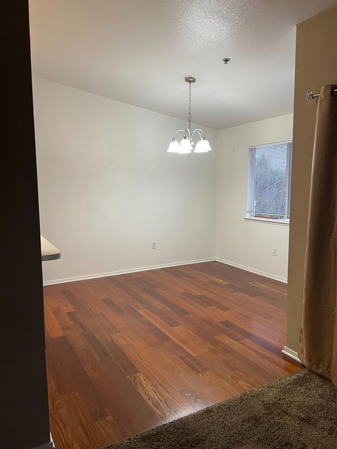 565 Peerless Way, Unit 302 Tracy, CA 95376 - Photo 8 of 17 a view of an empty room with a chandelier fan and wooden floor