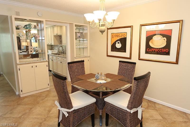 820 Ketch Drive, Unit 2 Naples, FL 34103 - Photo 4 of 17 Dining room featuring crown molding, sink, a notable chandelier, and light tile floors