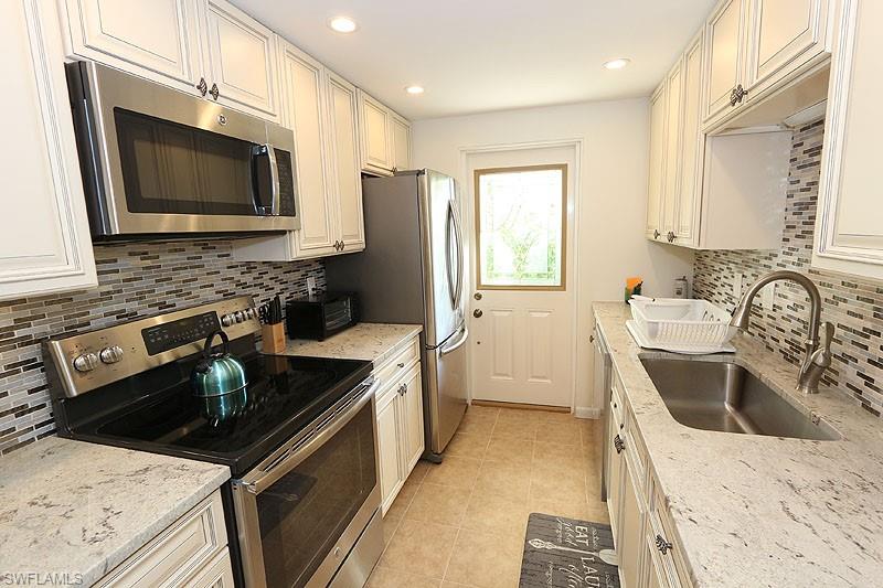 820 Ketch Drive, Unit 2 Naples, FL 34103 - Photo 6 of 17 Kitchen with stainless steel appliances, sink, tasteful backsplash, and light stone counters