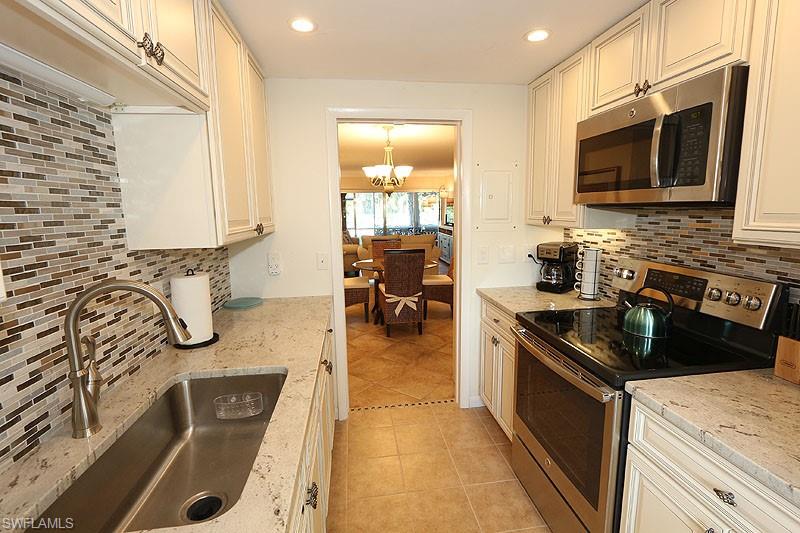 820 Ketch Drive, Unit 2 Naples, FL 34103 - Photo 7 of 17 Kitchen with backsplash, appliances with stainless steel finishes, sink, and light tile flooring