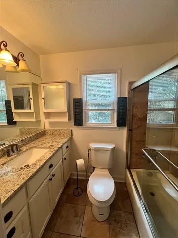 a bathroom with a granite countertop toilet sink and mirror
