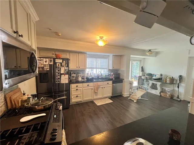 a kitchen with stainless steel appliances kitchen island granite countertop a stove refrigerator and cabinets with wooden floor