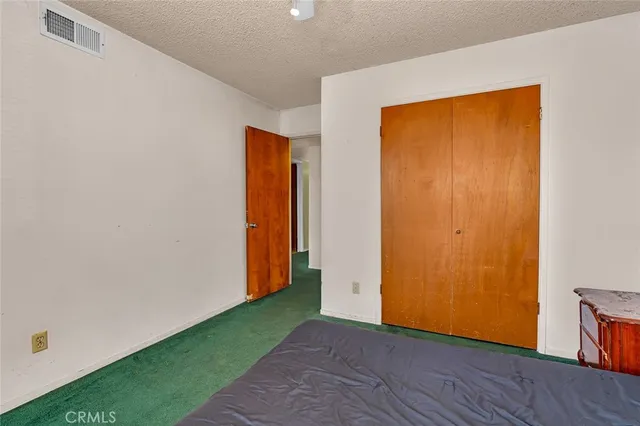 a view of an empty room with wooden floor and closet