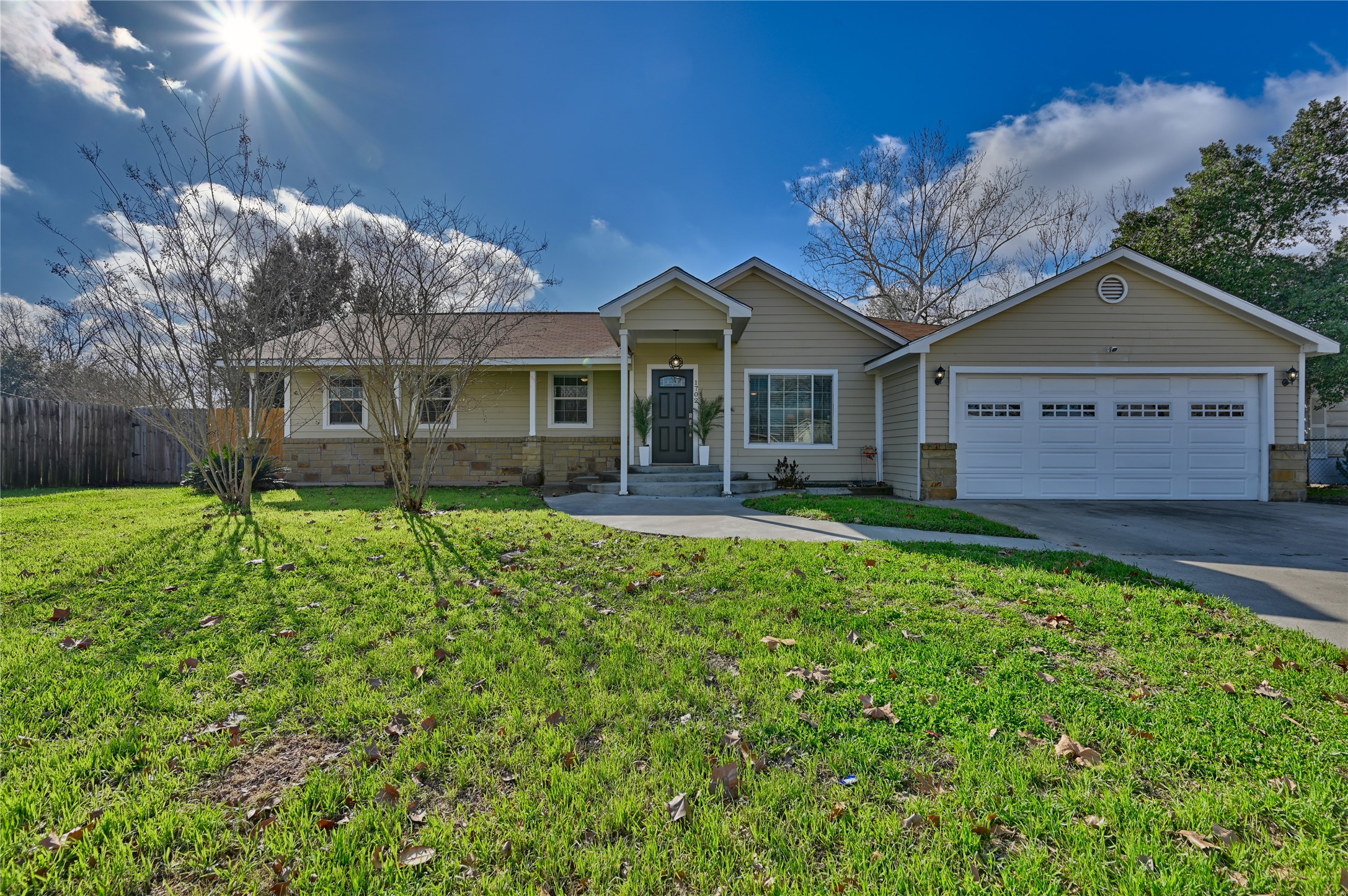 Ranch-style house featuring driveway, stone siding, and an attached garage