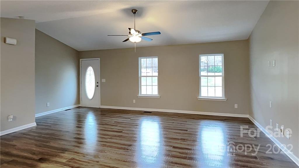 170 State Park Road Troutman, NC 28166 - Photo 3 of 11 an empty room with wooden floor chandelier and windows
