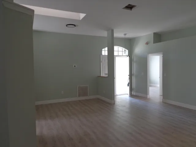 a view of an empty room with window and wooden floor