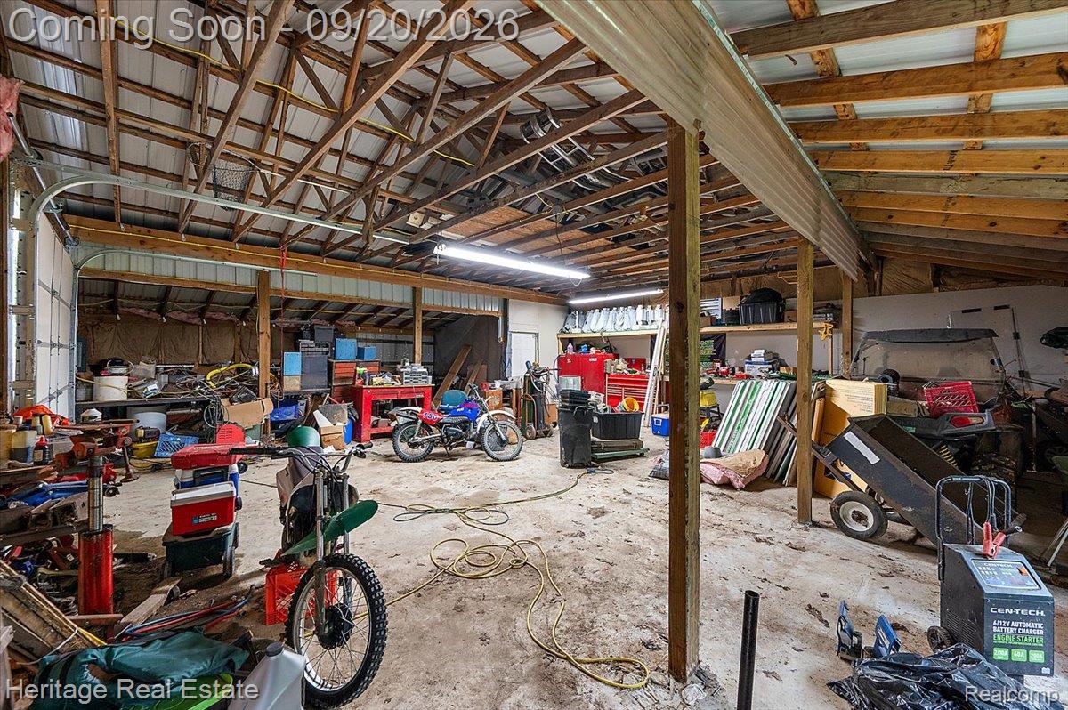 3337 Le Valley Road Columbiaville, MI 48421 - Photo 22 of 57 Large open-span utility building with a high-pitched roof, exposed wood trusses, and concrete flooring