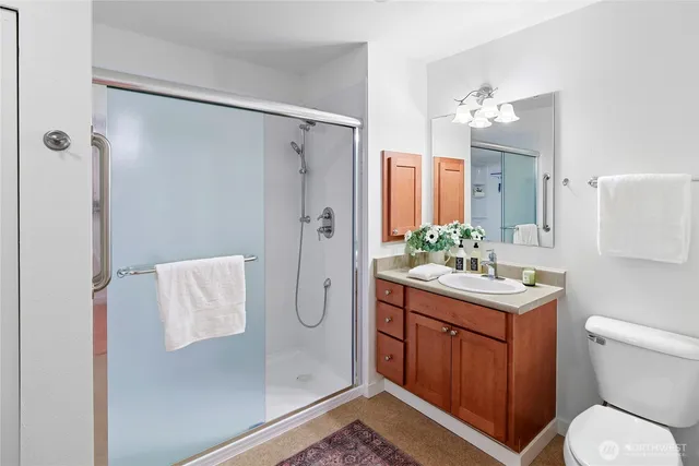 a bathroom with a granite countertop sink toilet a mirror a vanity and shower