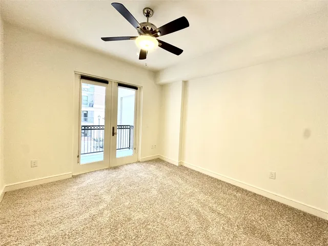 an empty room with windows and ceiling fan