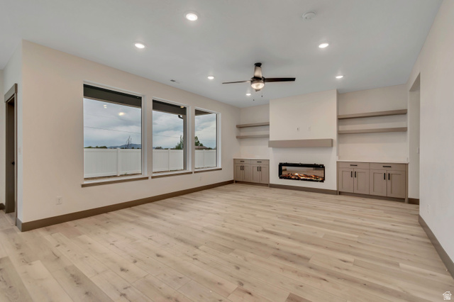 3317 South 1000 West, Unit 6010 Logan, UT 84321 - Photo 14 of 34 Unfurnished living room with ceiling fan, a glass covered fireplace, recessed lighting, and light wood-type flooring
