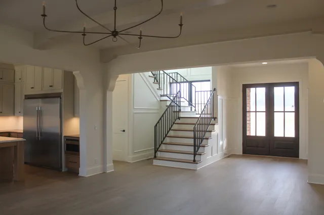 a view of an empty room with wooden floor and stairs