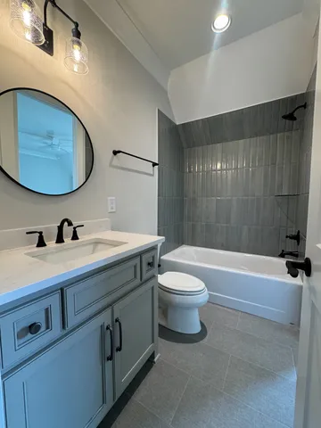 a bathroom with a double vanity sink toilet mirror and bathtub