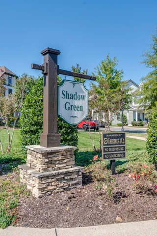 a white bench sitting in front of a brick house with a large tree