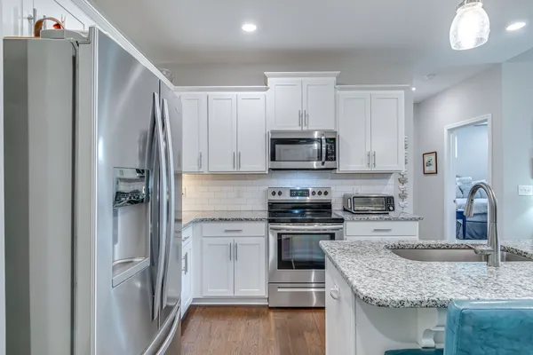 a kitchen with stainless steel appliances granite countertop a refrigerator sink and stove
