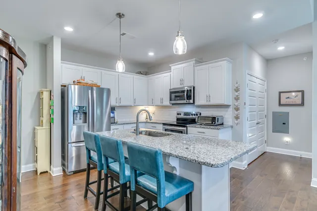 a kitchen with stainless steel appliances granite countertop a stove refrigerator a oven a sink with a dining table and chairs