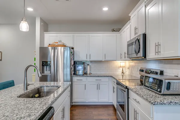 a kitchen with stainless steel appliances granite countertop a sink stove and refrigerator