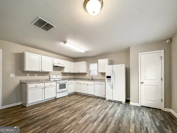 a kitchen with stainless steel appliances granite countertop a stove top oven a sink dishwasher and a refrigerator with wooden floor