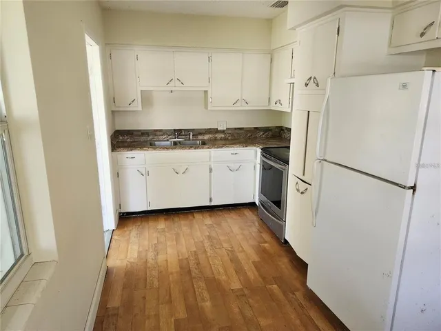 a kitchen with a refrigerator and white cabinets