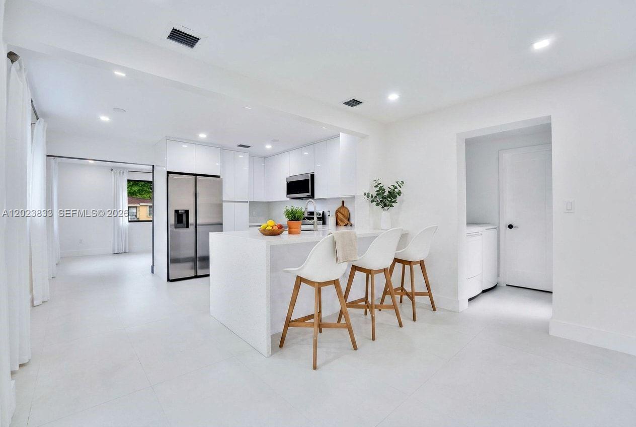 6566 Southwest 35th Street Miami, FL 33155 - Photo 12 of 36 a kitchen with stainless steel appliances kitchen island granite countertop a refrigerator and microwave