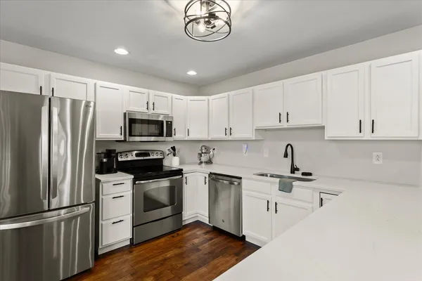 a kitchen with white cabinets stainless steel appliances and a sink