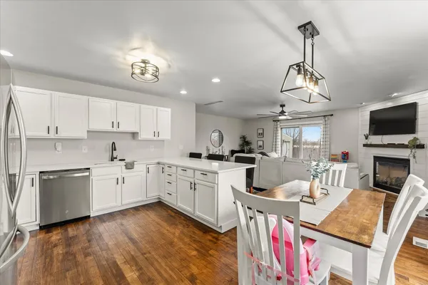 a open kitchen with stainless steel appliances granite countertop a stove top oven a sink dishwasher a dining table and chairs with wooden floor