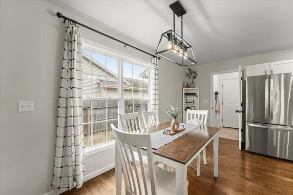 a dining room with wooden floor a chandelier a glass table and chairs