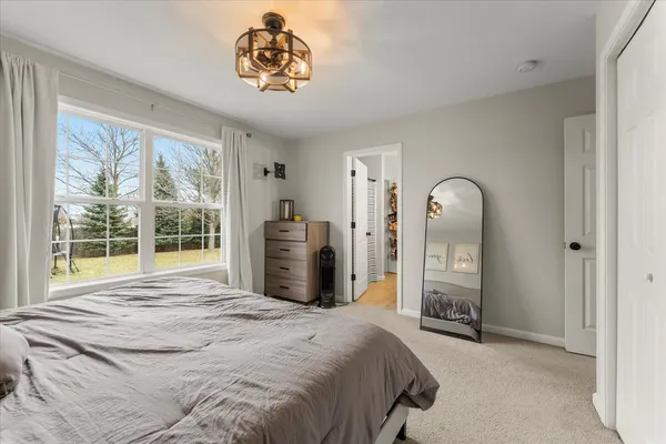 a bed sitting in a spacious bedroom next to a window