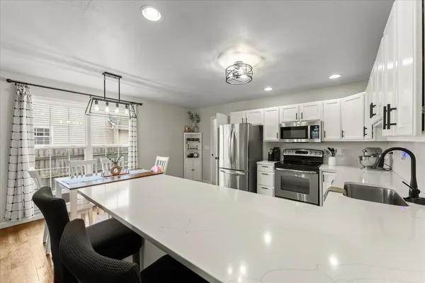 a kitchen with stainless steel appliances a dining table chairs stove refrigerator and microwave