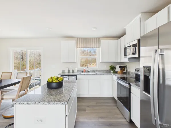 a kitchen with a refrigerator a stove a sink a dining table and chairs