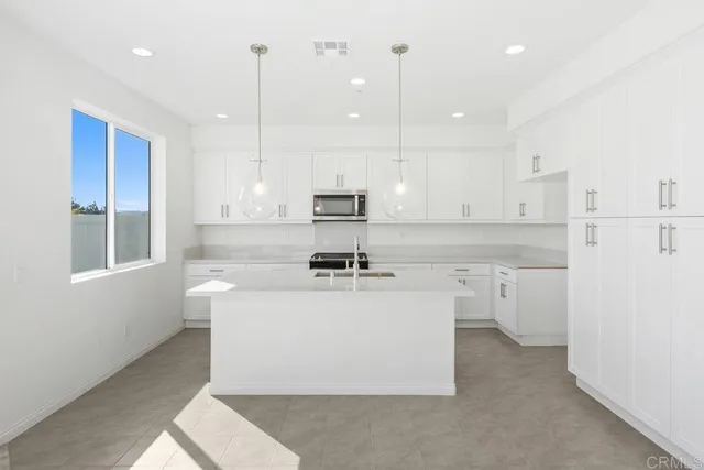 a kitchen with a sink a stove a refrigerator and white cabinets
