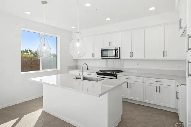 a kitchen with stainless steel appliances granite countertop a sink a stove a refrigerator a center island and a window