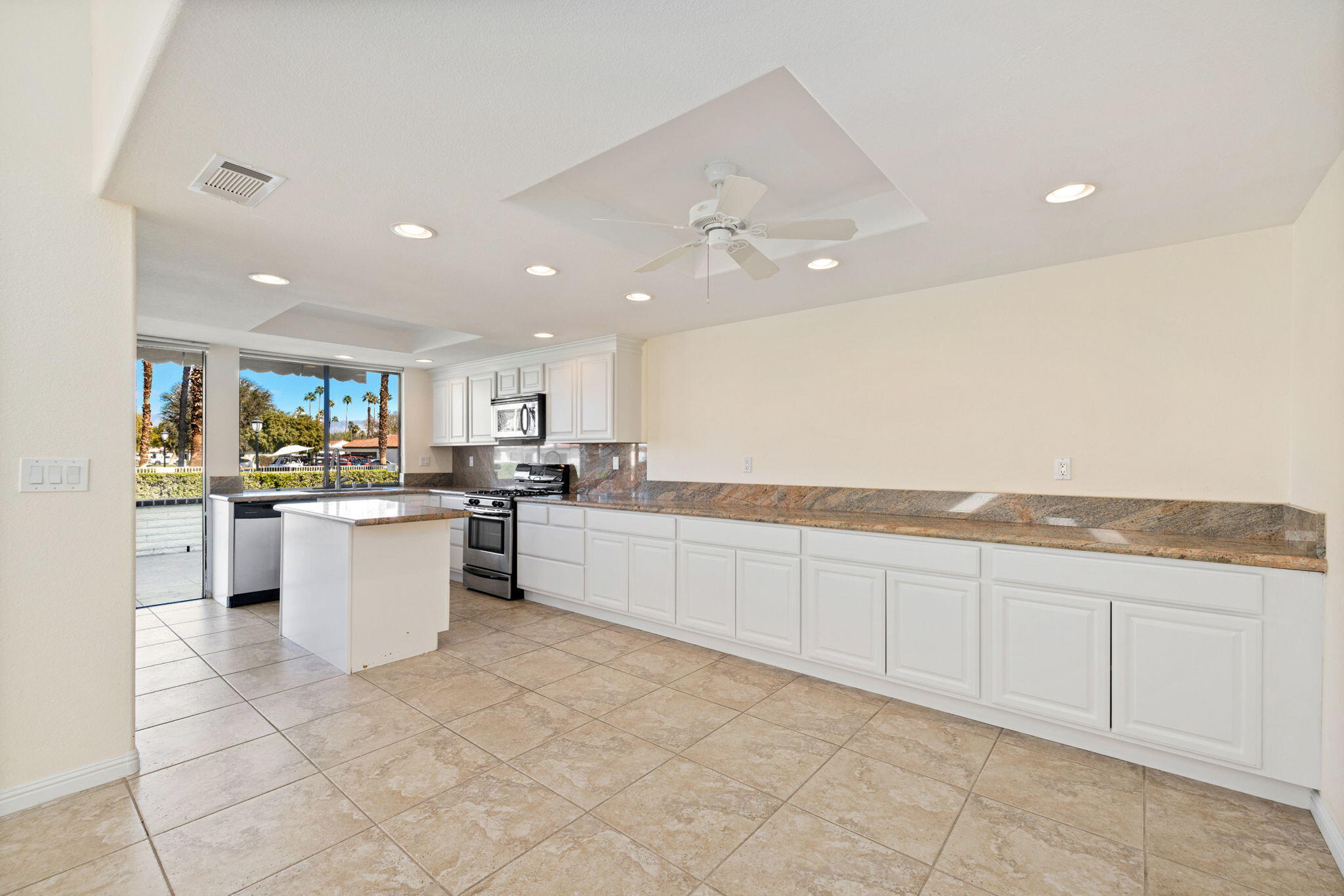 70 Durango Circle Rancho Mirage, CA 92270 - Photo 10 of 39 a large white kitchen with kitchen island a sink a stove a dining table and chairs