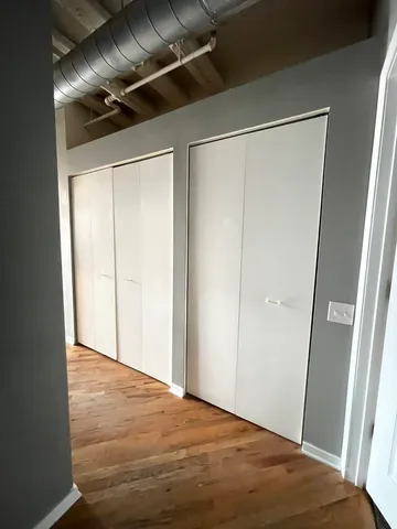 an empty room with a chandelier fan and kitchen view