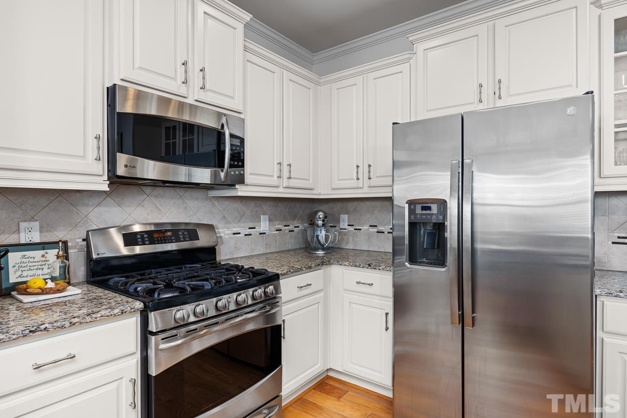 5528 Wade Park Boulevard Raleigh, NC 27607 - Photo 11 of 30 a kitchen with stainless steel appliances granite countertop a stove a refrigerator and a white cabinets