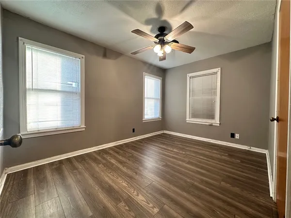 a view of an empty room with a window and wooden floor