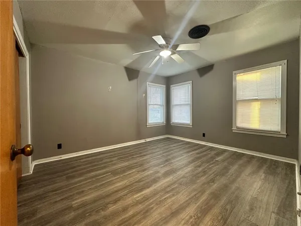 a view of an empty room with a window and wooden floor