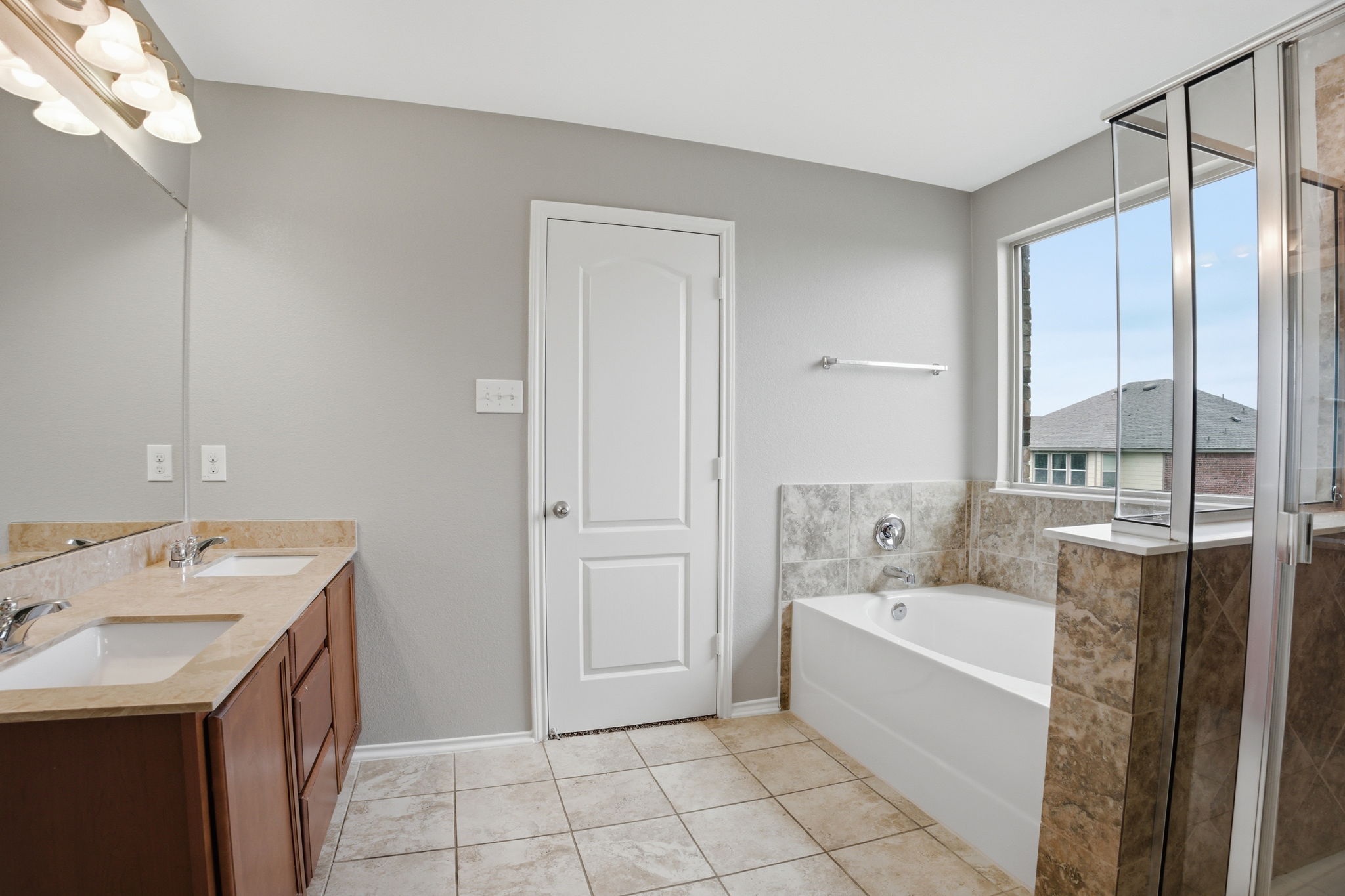 670 Landon Samuel Loop Pflugerville, TX 78660 - Photo 10 of 22 Bathroom featuring a dual vanity with undermount sinks and a neutral countertop, a built-in bathtub with a tiled surround, a separate glass-enclosed shower, a window, and neutral tile flooring