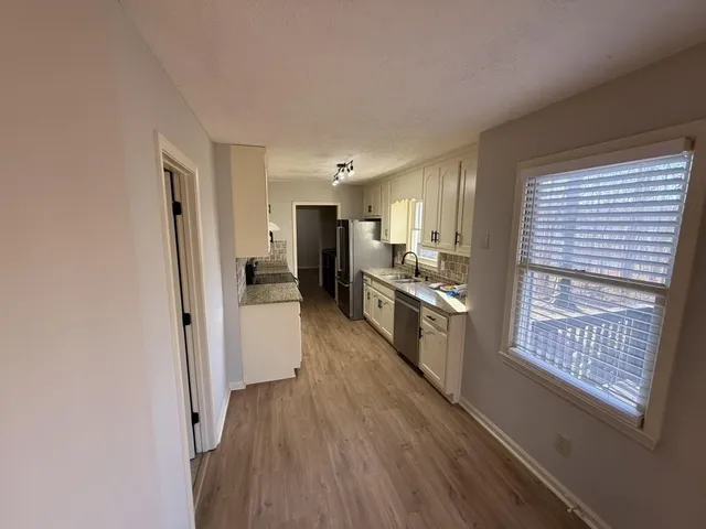 a large kitchen with a wooden floor and stainless steel appliances