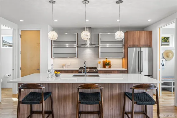 a kitchen with stainless steel appliances granite countertop a sink a stove and a refrigerator with wooden floor