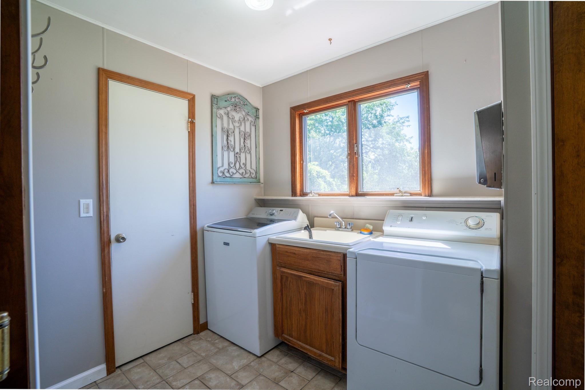 12900 Maxwell Road Carleton, MI 48117 - Photo 39 of 59 Functional utility room featuring a large window, tiled flooring, and a built-in sink with cabinetry