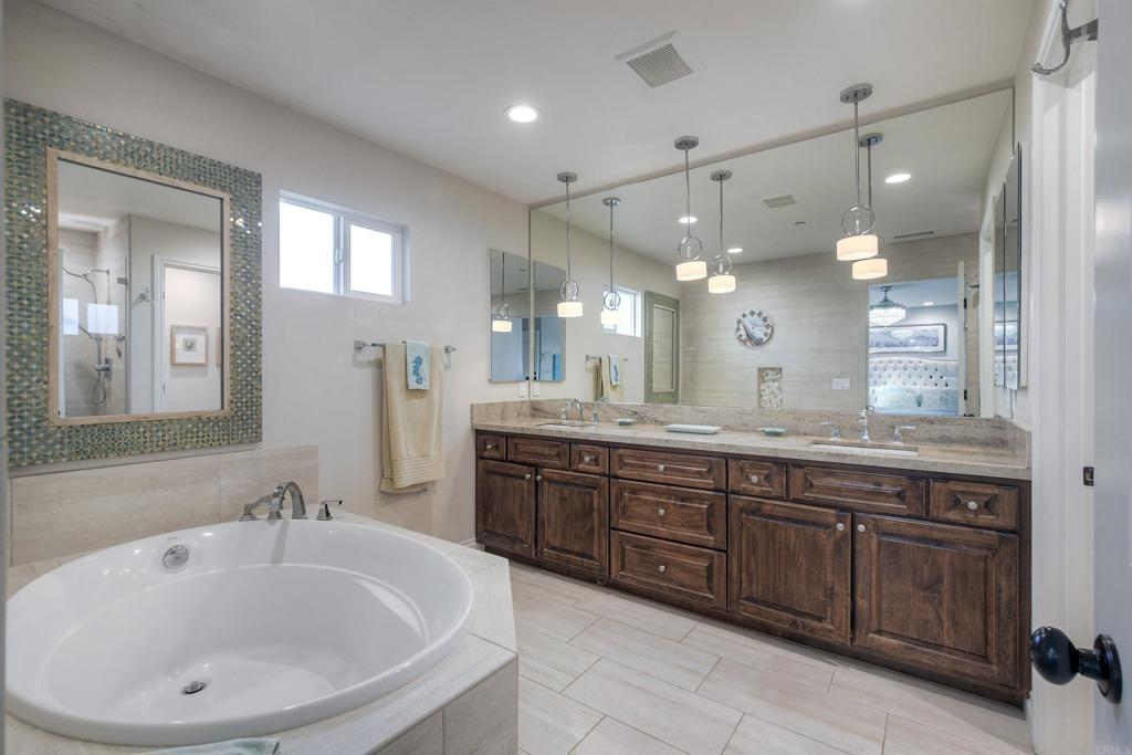 917 Santo Way Cardiff-by-the-Sea, CA 92007 - Photo 18 of 43 a large bathroom with a double vanity sink a large mirror and a bathtub