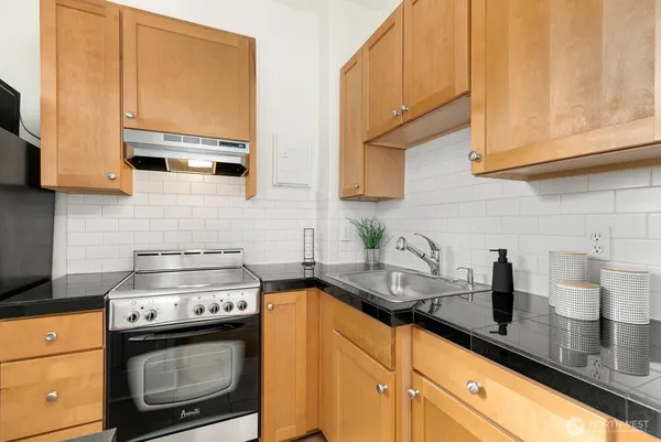 a kitchen with granite countertop a sink a stove and cabinets