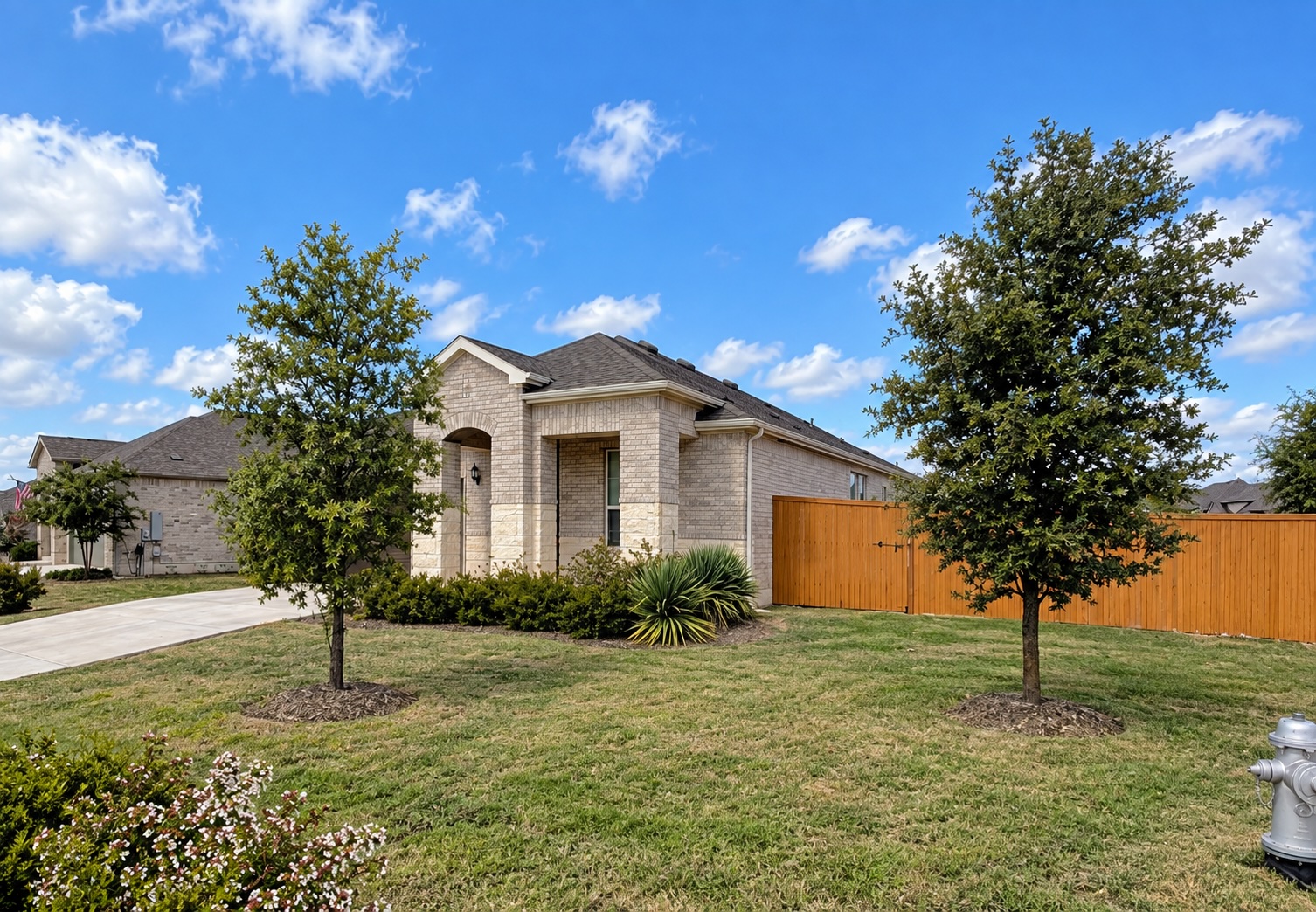 268 Fish Trap Road Dripping Springs, TX 78620 - Photo 3 of 23 A classic brick exterior sits framed by neat landscaping and a wooden privacy fence.
