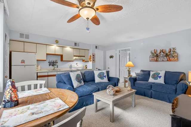 a living room with furniture kitchen view and a chandelier