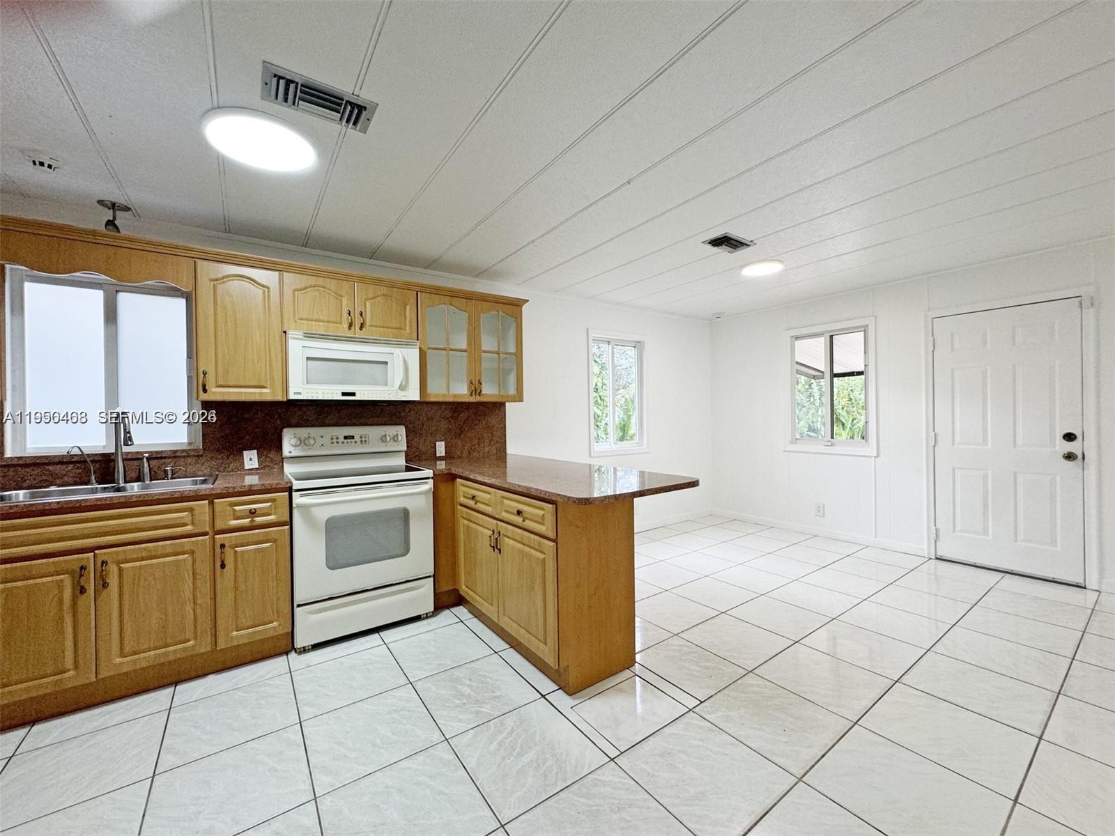 2982 Northwest 95th Street Miami, FL 33147 - Photo 7 of 30 a kitchen with stainless steel appliances granite countertop a stove a sink and a refrigerator