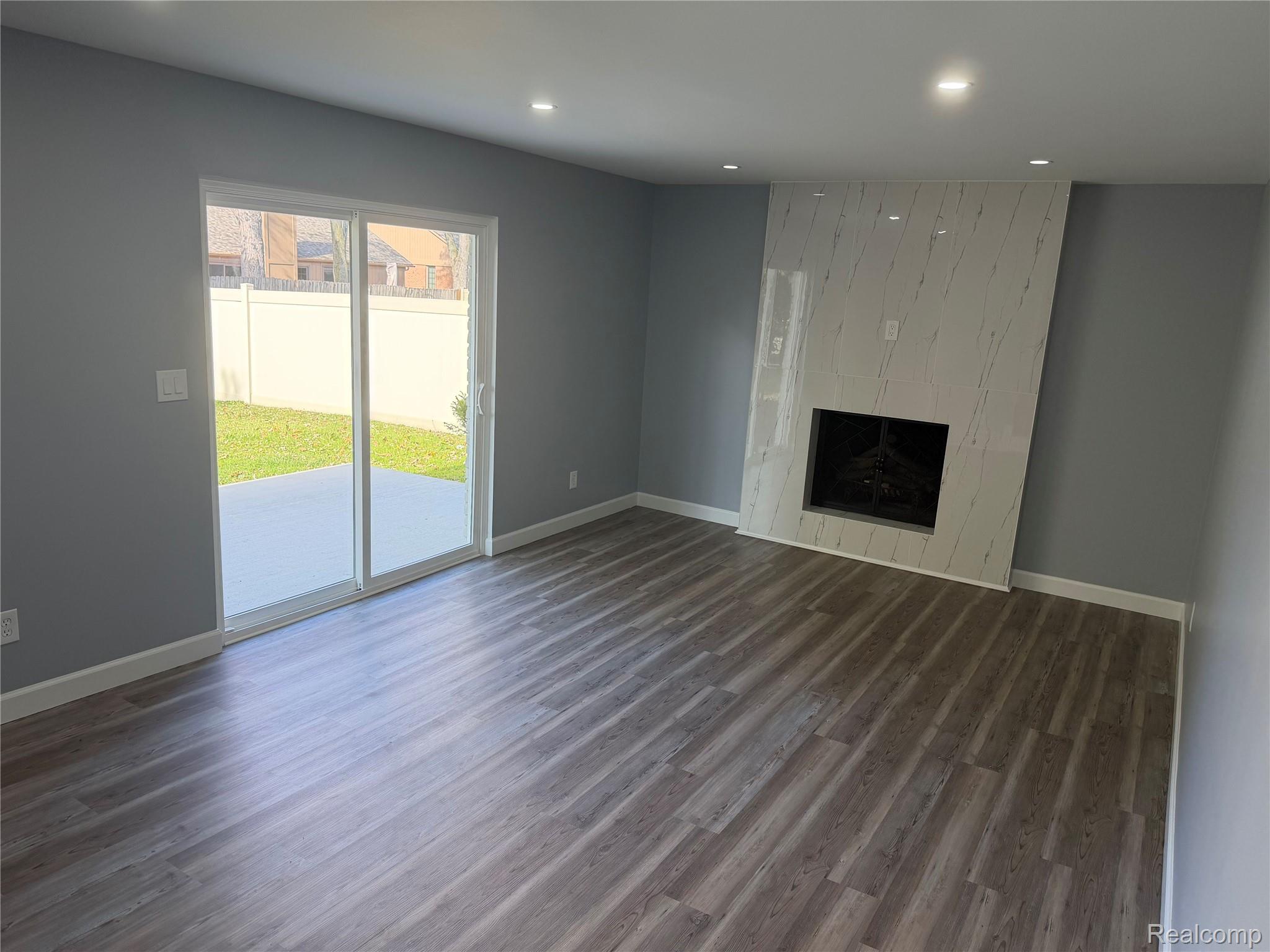 20698 Coachwood Road Riverview, MI 48193 - Photo 9 of 37 Unfurnished living room with wood finished floors, recessed lighting, and a tiled fireplace