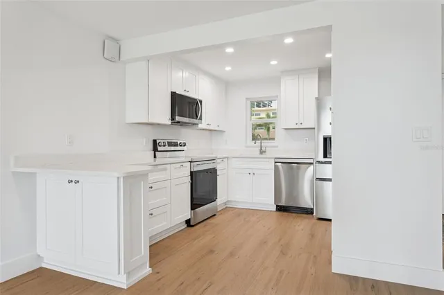 a kitchen with white cabinets stainless steel appliances and sink