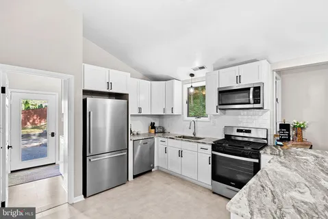 a kitchen with a refrigerator a microwave a sink and cabinets