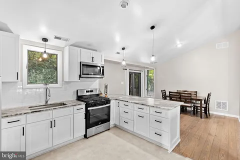 a kitchen with granite countertop a sink a counter space appliances and cabinets